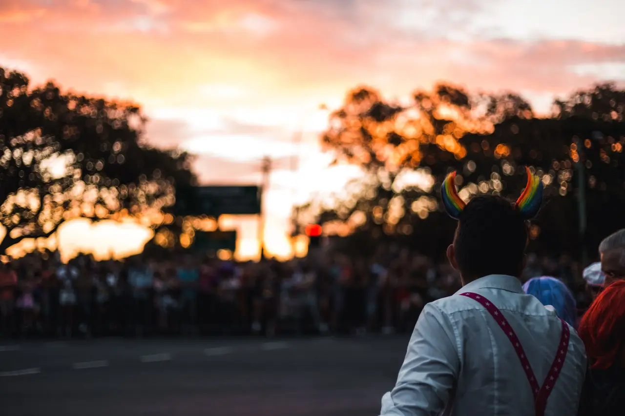 A Pride crowd gathered in the street at golden hour.